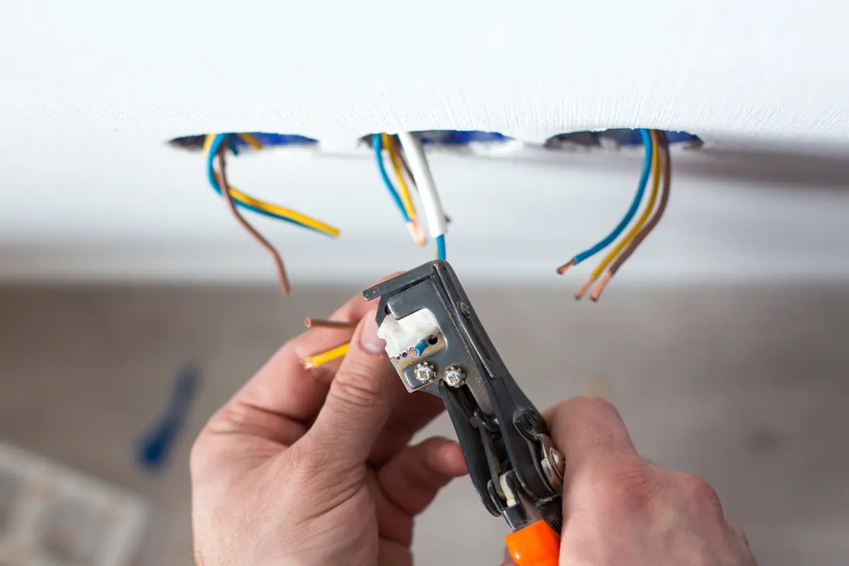 Hands terminating cable at ceiling boxes