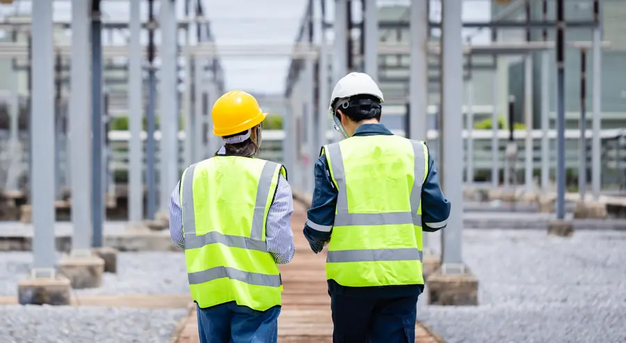 Two people in high-visibility vests walking an electrical inspection