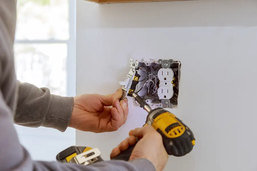 An electrician wiring a wall outlet during a repair